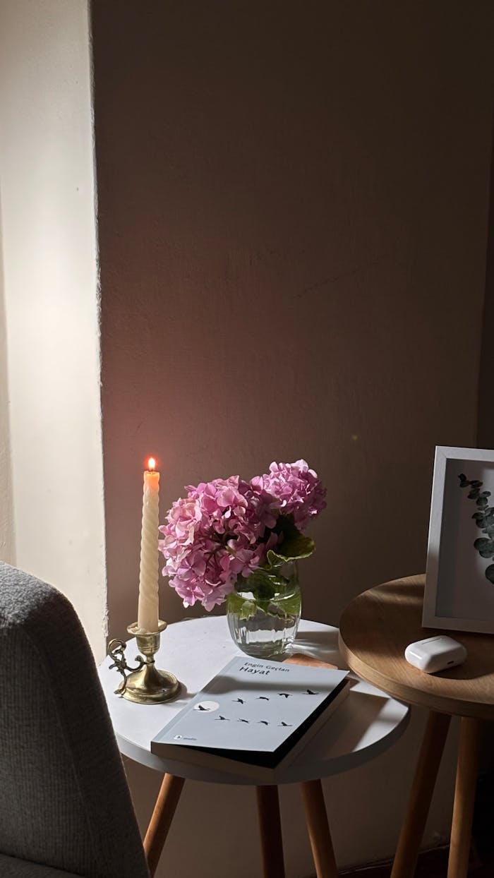 A serene indoor setting with pink hydrangeas, lit candle, and modern decor creating a cozy atmosphere.