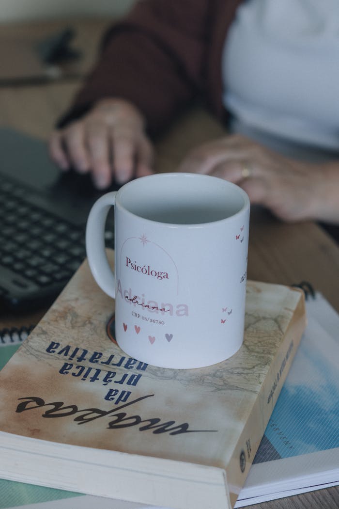 Close-up of a psychologist's mug on books, next to a laptop on a desk.